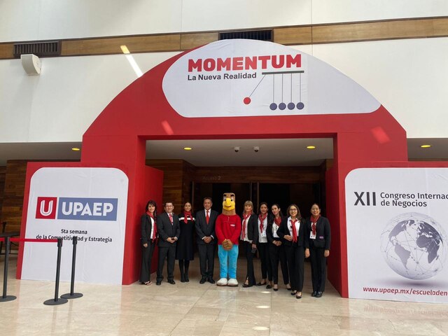 Nueve personas posando para una fotografia con la mascota de la escuela UPAEP la cual es un aguila